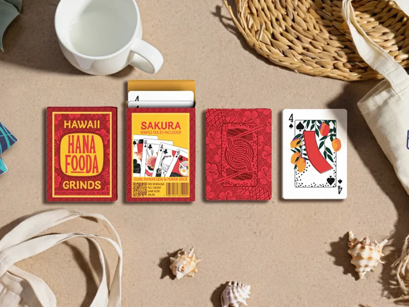 overhead lifestyle shot of the cards and box on sand with common tropical items like sea shells